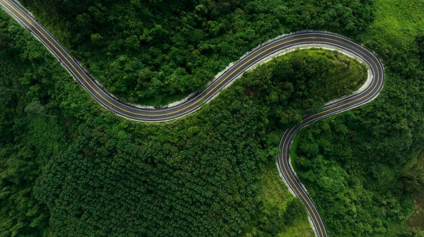 aerial top view beautyfull curve road on green forest in the rain season background, rural routes connecting cities in the north of thailand
