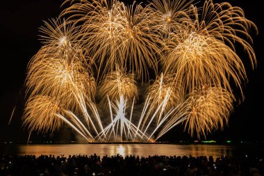 PATTAYA, CHONBURI, THAILAND Pattaya Uluslararası Havai fişek Festivali 'nde güzel renkli bir gece sahnesi ve beac' ta havai fişek gösterisi yapan turist görünümlü siluet grubu.