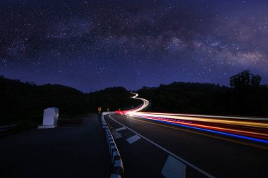  Gece mavi gökyüzü ve galaksi sahnesinde uzun pozlu araba ışığı ya da yıldız samanyolu arka planında, 1081 numaralı virajlı yolda - Bo Kluea Bölgesi, Tayland 'da. Turistler için popüler yerler