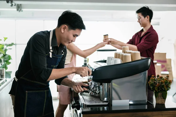 asian man bartender mixing and pouring coffee into cup from coffee machine at counter in small coffee shop business stratup concept, cinema film tone process