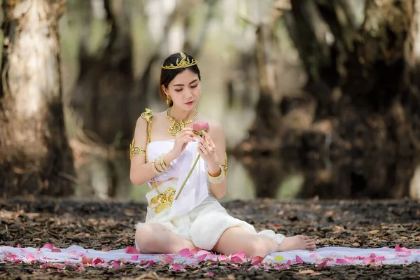 白いドレスで美しいタイのアジアの女性地元の伝統衣装名前はナキー 座っていると植物園タイランドでハスを保持 ナキーは公園のコンセプトでリラックス — ストック写真