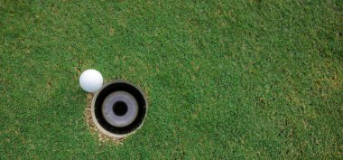 Top views white golf ball and golf hole on green grass texture background. coppy space for web page,
