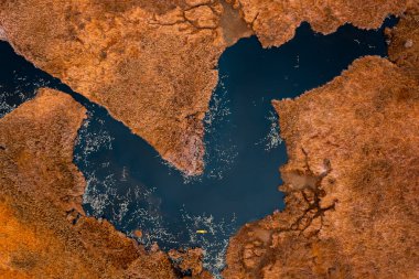 Kara gölde kayak yapan küçük turist ve kuru turuncu çayır manzaralı, bakış açısına sahip fotoğrafçı dronu.,