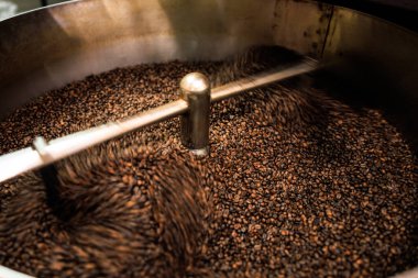 Taze kahve çekirdekleri kavrulmuş dönen profesyonel makine yumuşak odaklı yavaş deklanşör hızına yakın çünkü kahve çekirdeklerinin hareket bulanıklığı konseptini yapmak istiyorum, fabrika chiang rai Thailand 'da, açı açılı çekim.