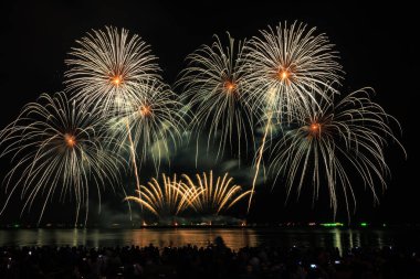 PATTAYA, CHONBURI, THAILAND Pattaya Uluslararası Havai fişek Festivali 'nde güzel renkli bir gece sahnesi ve bir grup turist plajda havai fişek gösterisinin fotoğraflarını çekiyorlar.