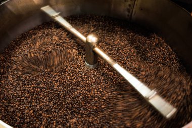 Taze kahve çekirdekleri kavrulmuş dönen profesyonel makine yumuşak odaklı yavaş deklanşör hızına yakın çünkü kahve çekirdeklerinin hareket bulanıklığı konseptini yapmak istiyorum, fabrika chiang rai Thailand 'da, açı açılı çekim.