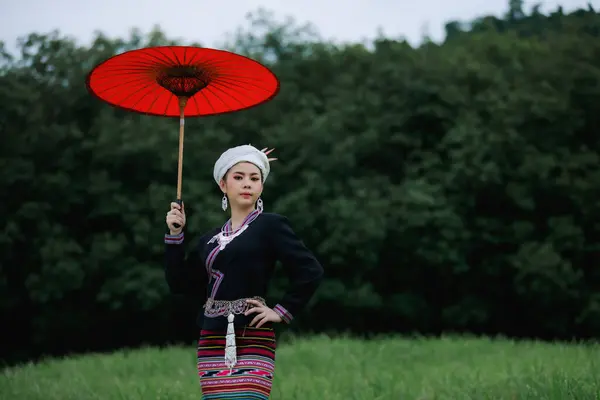 亚洲年轻女子的肖像 身穿传统的泰族文化长裙 穿着红色雨伞手牵手站在自然花园 绿林背景下 — 图库照片