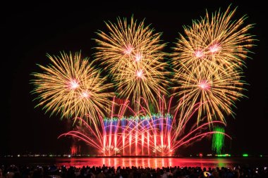 PATTAYA, CHONBURI, THAILAND Pattaya Uluslararası Havai fişek Festivali 'nde güzel renkli bir gece sahnesi ve bir grup turist plajda havai fişek gösterisinin fotoğraflarını çekiyorlar.