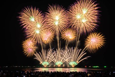 PATTAYA, CHONBURI, THAILAND Pattaya Uluslararası Havai fişek Festivali 'nde güzel renkli bir gece sahnesi ve bir grup turist plajda havai fişek gösterisinin fotoğraflarını çekiyorlar.