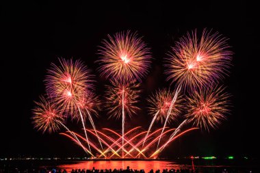 PATTAYA, CHONBURI, THAILAND Pattaya Uluslararası Havai fişek Festivali 'nde güzel renkli bir gece sahnesi ve bir grup turist plajda havai fişek gösterisinin fotoğraflarını çekiyorlar.