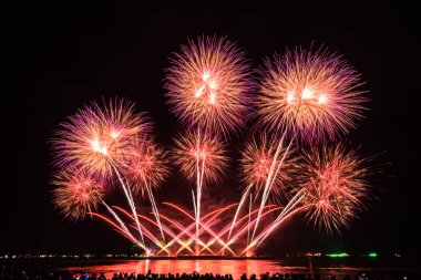 PATTAYA, CHONBURI, THAILAND Pattaya Uluslararası Havai fişek Festivali 'nde güzel renkli bir gece sahnesi ve bir grup turist plajda havai fişek gösterisinin fotoğraflarını çekiyorlar.