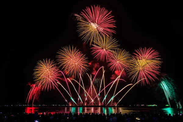 PATTAYA, CHONBURI, THAILAND Pattaya Uluslararası Havai fişek Festivali 'nde güzel renkli bir gece sahnesi ve bir grup turist plajda havai fişek gösterisinin fotoğraflarını çekiyorlar.