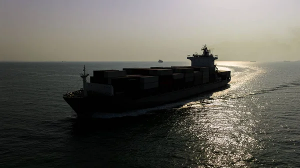 silhouette cargo container ship sailing in sea to import export goods and distributing products to dealer and consumers worldwide, by container ship Transport, business logistic delivery service, aerial view