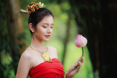  Portrait of Beautiful woman in traditional Thai red dress and holding lotus flower in her hand in the nature black background,  clipart