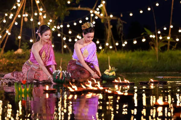 งไทยสองคนถ อกวางทองน งอย บนแพร มแม งเอเช ยในช ดไทยด งเด ากวางทองมาลอยในว — ภาพถ่ายสต็อก