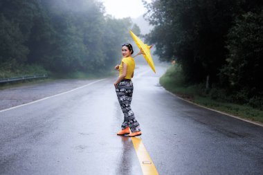 Yağmur mevsiminde yolun ortasında ayakta duran ve umblella tutan genç kadın portresi, doğal orman ve konsept.. 