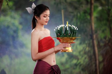 Antik Tayland kırmızısı elbiseli genç bir kadın. Krathong 'u elinde tutuyor..