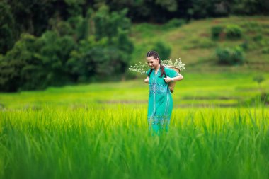 Kız turist ve çiçek sepeti yağmur mevsiminde Ban Pa Bong Piang, Chiang Mai Tayland 'da pirinç terasında mutlu bir şekilde yürüyor., 