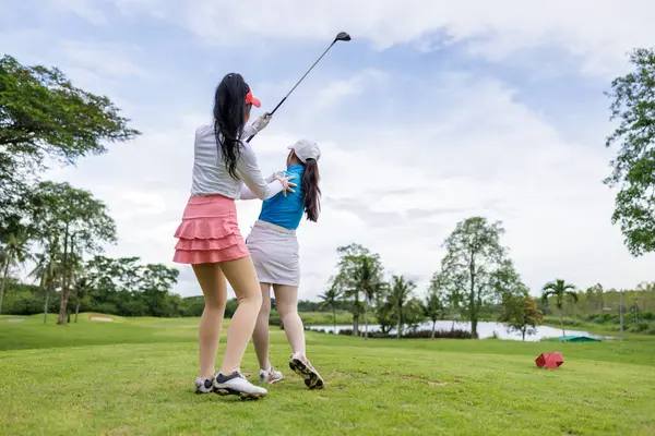 woman coachs are teaching and training asian female golfers in golf courses,