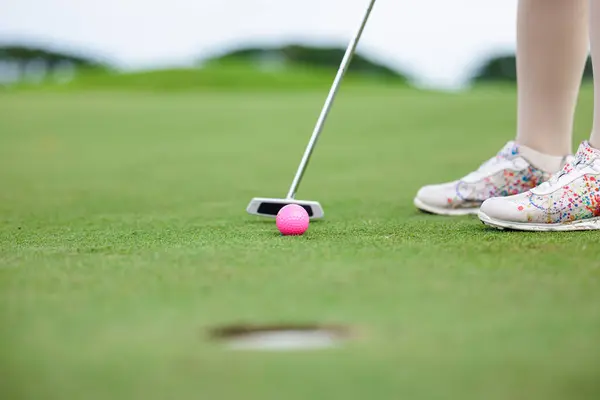 Professional woman golfer teeing golf in golf tournament competition at golf course, selective focus on golf ball,