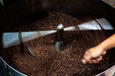 Kahverengi kahve çekirdekleri ve kavrulmuş döner kapaklı profesyonel makine, yumuşak odaklanmaya yakın hareket ve kahve çekirdekleri detay konsepti için düşük hız fotoğraf çekin