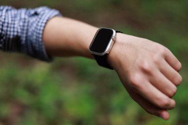 Yaklaş, akıllı saat serisi kullanan adam, akıllı saatini ormanda kuruyor, hedef başarısı, spor ve spor kavramı doğada..