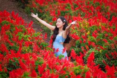 Kızıl çiçek bahçesinde çok mutlu genç bir kadının portresi.. 