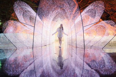 İçerideki genç Asyalı kadın ışık tünelinde çiçek izleri gösteriyor ki Nasatta Park, Ratchaburi, Tayland