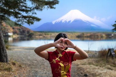 Genç Asyalı kadın gezgin Fuji Gölü 'nün kenarında geleneksel kırmızı elbiseler giyiyor Japonya' daki Fuji Dağı arka planında..