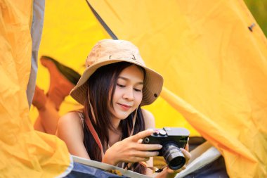 Safari elbiseli ve elinde kamera olan Asyalı genç bir turist sabah vakti çadırın içinde uzanıyordu.