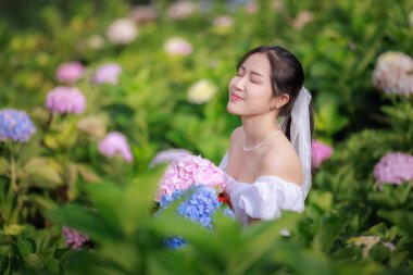 Renkli ortanca çiçekleri tarlasında beyaz elbiseli güzel bir kadın, zevk portresi ve rahatlama boş zaman konsepti..