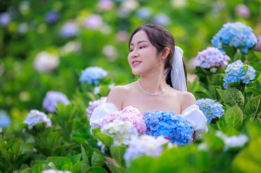 Renkli ortanca çiçekleri tarlasında beyaz elbiseli güzel bir kadın, zevk portresi ve rahatlama boş zaman konsepti..