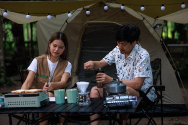 Maceracı genç Asyalı çift kamp alanlarında sabah kahvaltısı için tost ve kahve hazırlıyorlar..