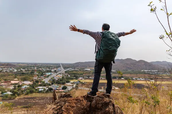 Bir erkek gezginin tepenin üstünde dikiz üstü duruşu, bir sırt çantası taşıması, ve aşağıdaki manzaraya bakması, bir yol, küçük bir kasaba ve uzak dağları kapsıyor. Bu bir macera ve keşif duygusu taşır..