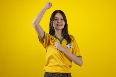 2022 Katar Kupası 'nda Brezilya futbol takımının resmi formasını giyen ve stüdyo fotoğrafında Brezilya bayrağı taşıyan bir kadın. Brezilyalı taraftar.