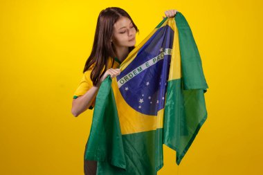 2022 Katar Kupası 'nda Brezilya futbol takımının resmi formasını giyen ve stüdyo fotoğrafında Brezilya bayrağı taşıyan bir kadın. Brezilyalı taraftar.