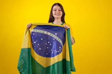 2022 Katar Kupası 'nda Brezilya futbol takımının resmi formasını giyen ve stüdyo fotoğrafında Brezilya bayrağı taşıyan bir kadın. Brezilyalı taraftar.