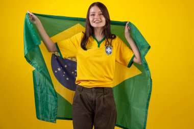 2022 Katar Kupası 'nda Brezilya futbol takımının resmi formasını giyen ve stüdyo fotoğrafında Brezilya bayrağı taşıyan bir kadın. Brezilyalı taraftar.
