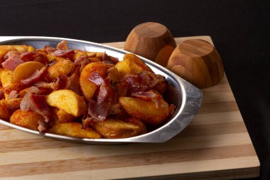 Biberli kızarmış patates ve ahşap bir tahtanın üstünde gümüş bir kasede domuz pastırması. Geleneksel Brezilya atıştırmalıkları