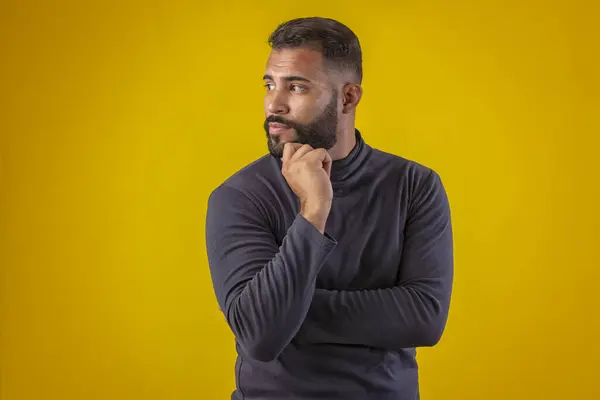 Sakallı, siyah tişörtlü, farklı yüz ifadeleri olan bir adam.