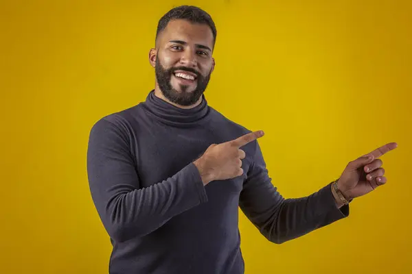 Sakallı, siyah tişörtlü, farklı yüz ifadeleri olan bir adam.