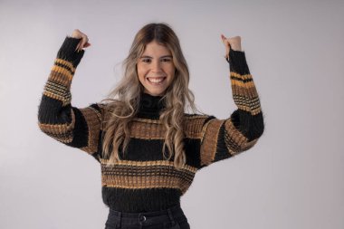 Stüdyo fotoğrafında bluz ve etek giyen genç bir kadın komik pozlar veriyor.