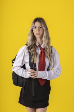 Klasik öğrenci kıyafeti, etek, kravat ve uzun kollu gömlek giyen, sonu gelmeyen bir geçmişi olan, komik pozlar veren genç bir kız..