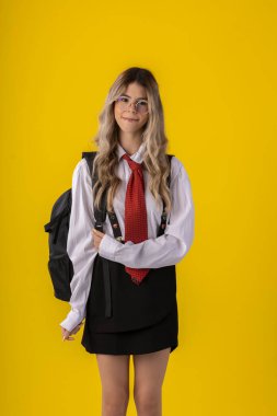 Klasik öğrenci kıyafeti, etek, kravat ve uzun kollu gömlek giyen, sonu gelmeyen bir geçmişi olan, komik pozlar veren genç bir kız..