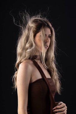 Siyah arka planda lüks bir elbise giyen genç sarışın kadın.