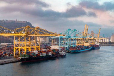 Barselona, İspanya - 28 Ekim 2022, konteynır kargo gemisi lojistiği ve nakliyesi ile birlikte gün batımında tersanede çalışan vinç köprüsü. Lojistik ihracat ve ulaşım sektörü geçmişi.