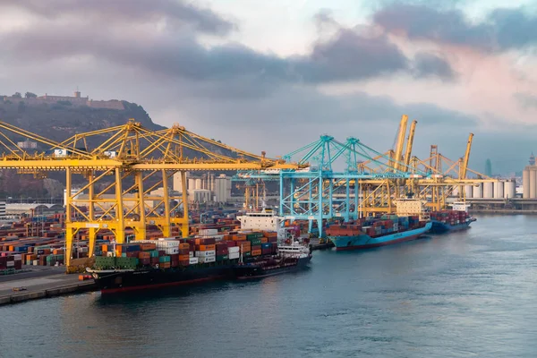 Barselona, İspanya - 28 Ekim 2022, konteynır kargo gemisi lojistiği ve nakliyesi ile birlikte gün batımında tersanede çalışan vinç köprüsü. Lojistik ihracat ve ulaşım sektörü geçmişi.