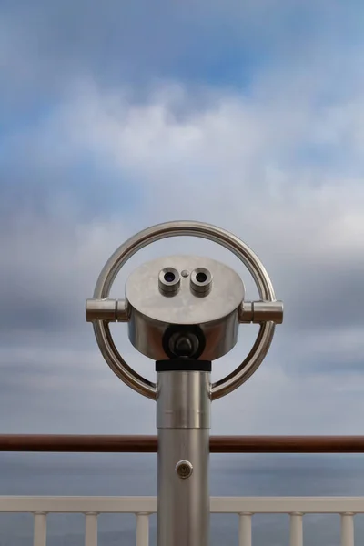 Close up of a fixed telescope at a vantage point against a cloudy sky, copy space, vertical