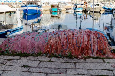 Rıhtımda uzanan renkli balık ağı, seçici odak ve bulanık port arkaplanı ile yakın plan fotoğrafı