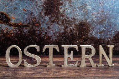 Rustic standing wooden letters with the inscription - Easter on a wooden background. Easter concept, copy space, closeup.